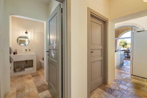 a hallway with a bathroom with a sink and a door at Tenuta Palù By Raro Villas in Carovigno