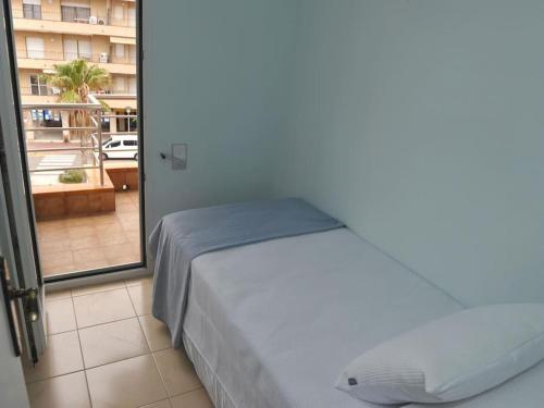 ein Bett in einem Zimmer mit einem großen Fenster in der Unterkunft Apto a 1 minuto de la Playa en Sant Antoni in Sant Antoni de Calonge