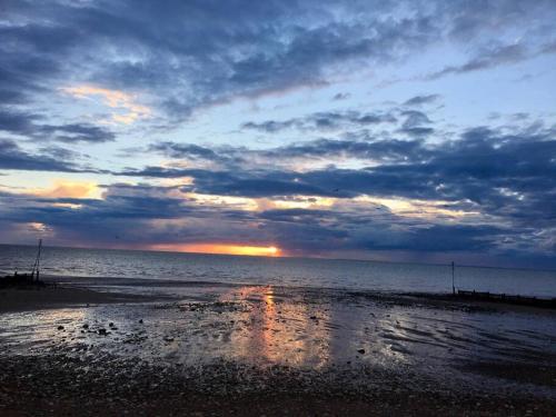 a sunset on a beach with a cloudy sky at Entire Cosy bungalow close to Beach in Heacham