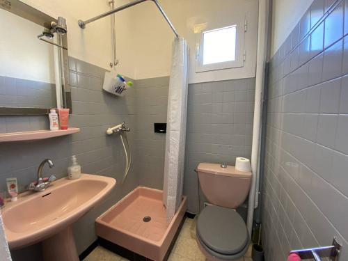 La salle de bains est pourvue de toilettes roses et d'un lavabo. dans l'établissement Superbe appartement avec vue mer, à Narbonne-Plage