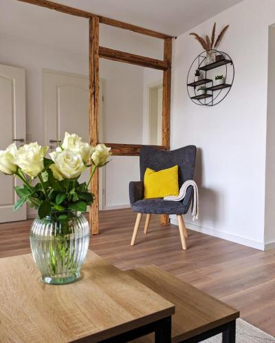 un salon avec un vase de fleurs et une chaise dans l'établissement Ferienwohnung Nikolaushof, à Oberbillig