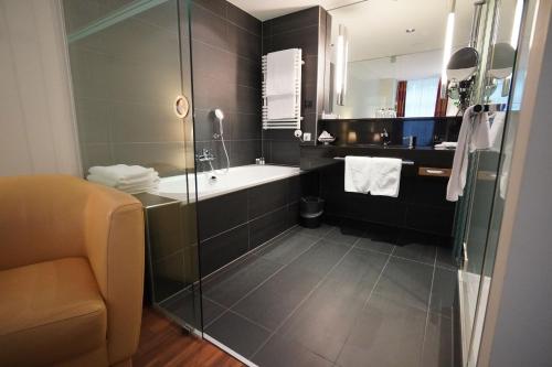 a bathroom with a shower and a tub and a sink at Hotel Glockenhof Zürich in Zürich