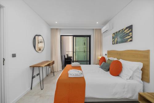 Schlafzimmer mit einem Bett mit orangefarbenen Kissen und einem Schreibtisch in der Unterkunft Terraços de Quarteira II Frolic by Real Properties in Cavacos