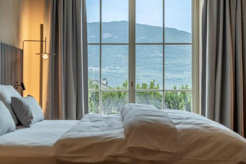 a bed in a hotel room with a large window at Ansitz Romani in Termeno