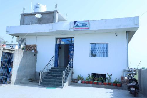 een wit gebouw met een trap en een deur bij OYO Shiv guru guest house in Bodh Gaya