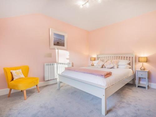 um quarto com uma cama branca e uma cadeira amarela em 2 Bed in Glenridding SZ178 em Glenridding