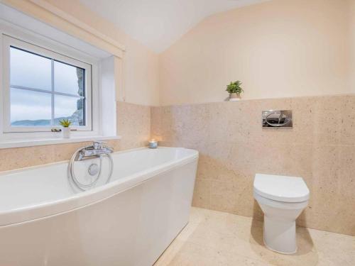 a bathroom with a tub and a toilet and a window at 3 Bed in Dockray SZ247 in Dockray