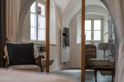 a bathroom with a sink and a chair and a mirror at Ansitz Romani in Termeno