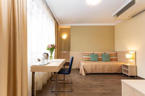 a room with a bed and a table and a desk at Geneva Hotel in Sofia
