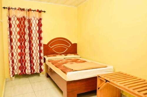 een kleine kamer met een bed en een gordijn bij Munnar Valley View in Munnar