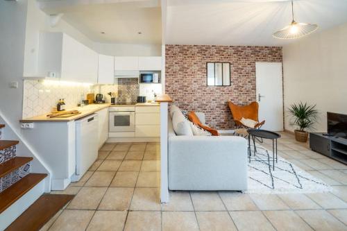 un salon avec un canapé blanc et une cuisine dans l'établissement Maison de Brique- CINEMA ROOM-BABY-FOOT - 10min à pieds Gare RER A- TRÈS PROCHE ARENA LA DEFENSE ET PARIS, à Houilles