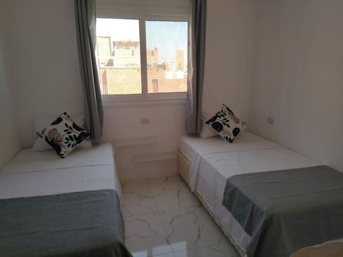 two beds in a room with a window at Condo with Breathtaking 's view with 2 bedrooms in Hurghada