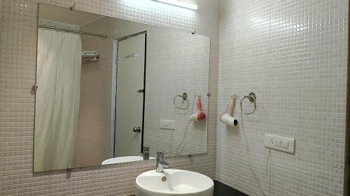 een badkamer met een wastafel en een spiegel bij VEENA REGENCY in Chās