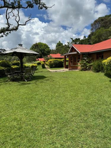 a house with a picnic table and an umbrella in a yard at Swiss Farm Cottage in Lushoto