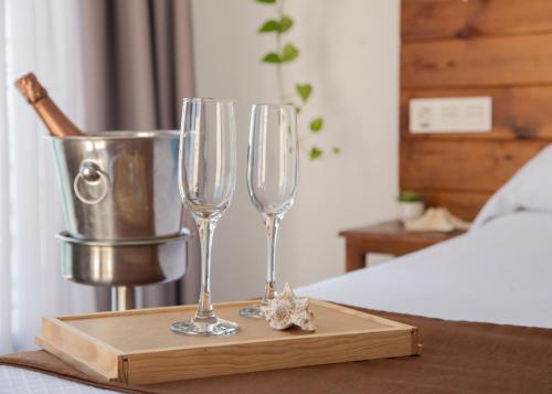 Hostal Boutique Casa del Mar Altea في ألتيا: كأسين من النبيذ على صينية خشبية على سرير