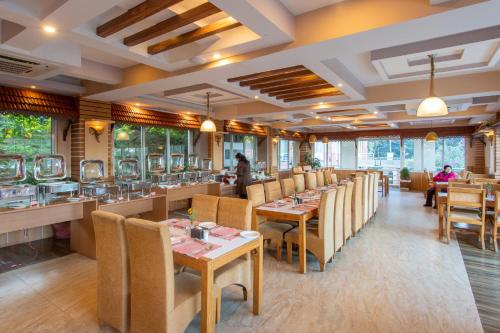 a restaurant with tables and chairs and people sitting at tables at Hotel Sarathi in Dhulikhel