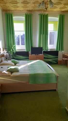 Schlafzimmer mit einem großen Bett und grünen Vorhängen in der Unterkunft Penzion U Bernardýna in Tachov