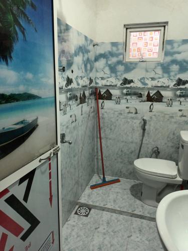 a bathroom with a toilet and a painting of a beach at white's vila in Matara