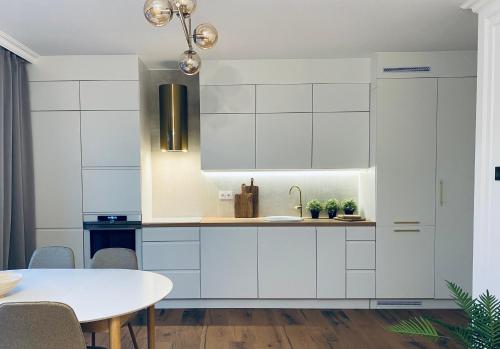 a kitchen with white cabinets and a table at Apartamenty Zuzanny in Mińsk Mazowiecki