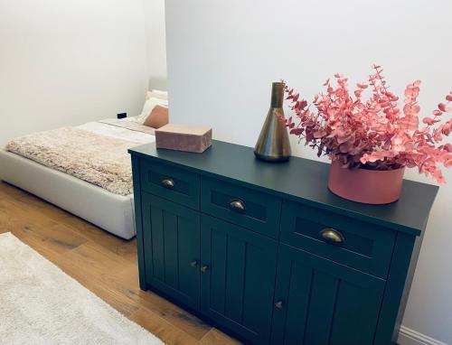 a blue dresser with a plant on it next to a bed at Apartamenty Zuzanny in Mińsk Mazowiecki