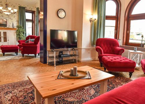 a living room with red chairs and a television at Ferienhaus Villa Heimfried Büsum in Büsum