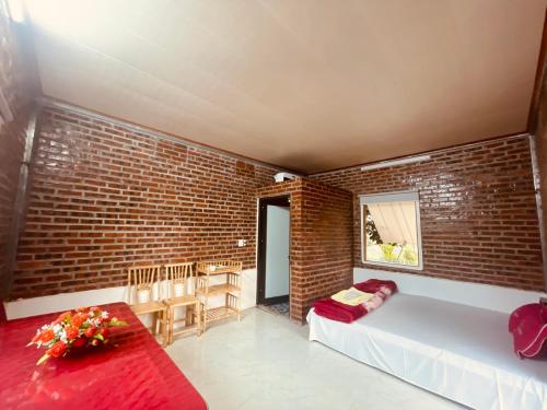 Habitación con paredes de ladrillo, cama y mesa. en Homestay Bách Thảo Tà Lùng, en Phục Hòa