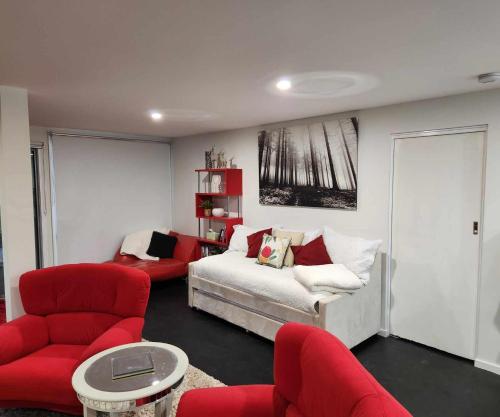 uma sala de estar com uma cama e cadeiras vermelhas em Whispering Woods Amore em Maryborough