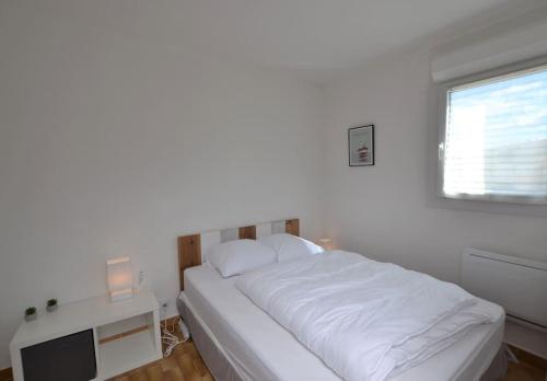 une chambre blanche avec un lit et une télévision dans l'établissement L'écrin au coeur de la citadelle, au Grau-du-Roi