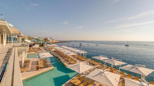 a resort with a pool and chairs and the ocean at AX ODYCY Hotel in St. Paul's Bay
