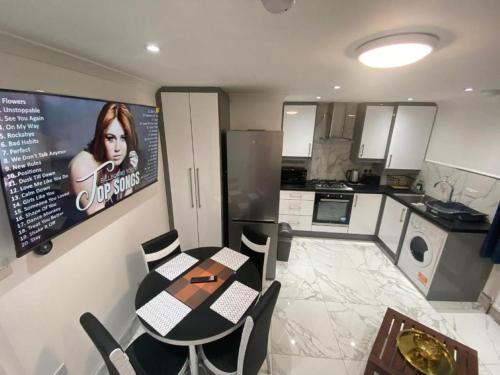 a kitchen with a table and chairs and a tv at THE ROYAL BOUTIQUE PICCADILLY LODGE by LONDON SLEEP 8 in Hayes