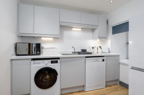 a white kitchen with a washing machine and a sink at Cornerstone Cottage in Laurencekirk