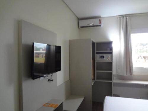 sala de estar con TV de pantalla plana en la pared en DE STEFANI HOTEL, en Portão