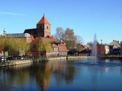 a river with a building and a church in the background at Ferienhaus am Mühlenteich in Teterow