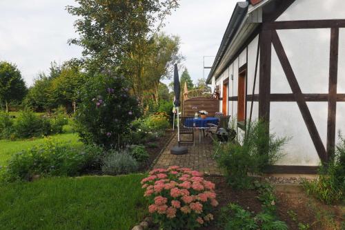 a garden with a table and flowers next to a house at Ferienwohnung auf dem Honighof in Krassow