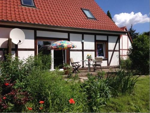 ein Haus mit einem Tisch und einem Sonnenschirm im Hof in der Unterkunft Ferienwohnung auf dem Honighof in Krassow