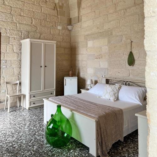 um quarto com uma cama branca e um vaso verde no chão em Le Casette nel Borgo em Borgagne