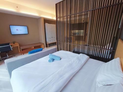 a bedroom with a white bed with a tv on the wall at Pines Studio Melaka Private Suites in Melaka