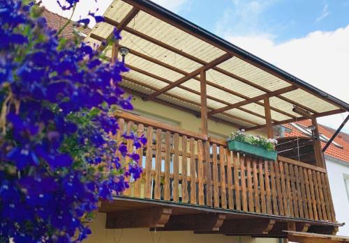 una terraza de madera con toldo en una casa con flores púrpuras en Tetjes Horstel - Ferienwohnung mit Balkon, en Teterow