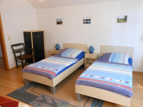 a bedroom with two beds and a chair in it at Pension im Oderbruch in Manschnow