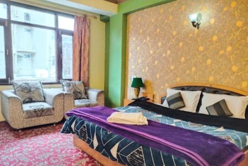um quarto com uma cama, uma cadeira e uma janela em Hotel Mehar Srinagar em Srinagar