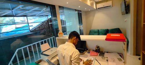 a man sitting at a desk in front of a computer at Grand Dyad Hotel - Near Kokilaben Hospital Andheri West in Mumbai