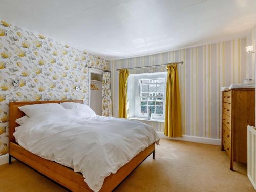 a bedroom with a large bed with yellow curtains at 3 Bed in Bridport 85255 in Puncknowle