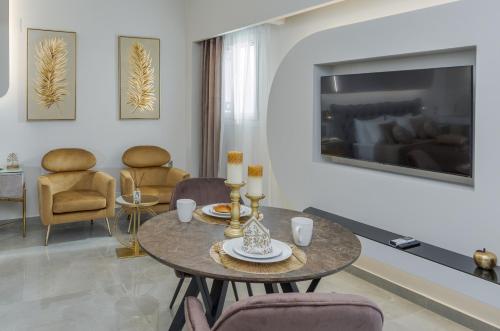 uma sala de estar com uma mesa e cadeiras e uma televisão em Myra Mare Suites by Estia em Amoudara Herakliou