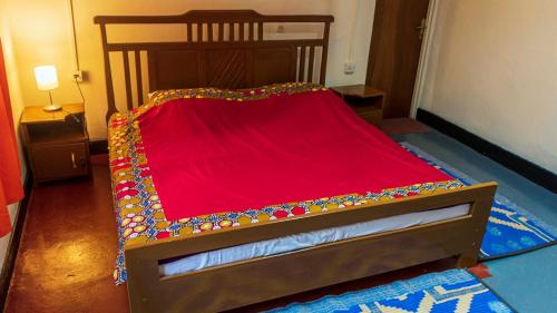 a small bed with a red blanket on it at Isange Paradise Resort in Ruhengeri