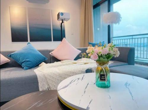 uma sala de estar com um sofá e um vaso de flores sobre uma mesa em 夜光城Mount·Austin·3Room·5Pax•Wifi. em Johor Bahru