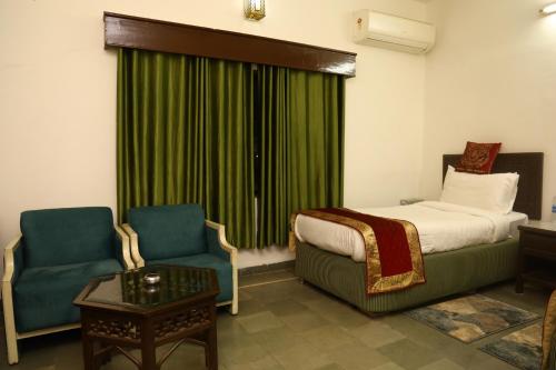 a hotel room with a bed and two chairs at Panna Tiger Resort- Riverside Property in Rājgarh