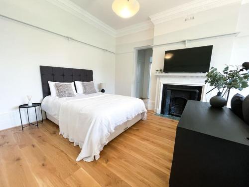Dormitorio blanco con cama y chimenea en Centrally located studio flat sleeps 4, en Ealing