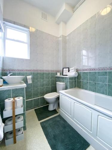 a bathroom with a tub and a toilet and a sink at Centrally located studio flat sleeps 4 in Ealing