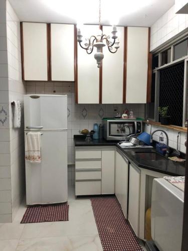 eine Küche mit einem weißen Kühlschrank und einer Mikrowelle in der Unterkunft Quarto privado em apartamento. in Vitória