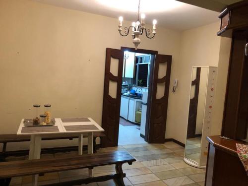 ein Esszimmer mit einem Tisch und einem Kronleuchter in der Unterkunft Quarto privado em apartamento. in Vitória